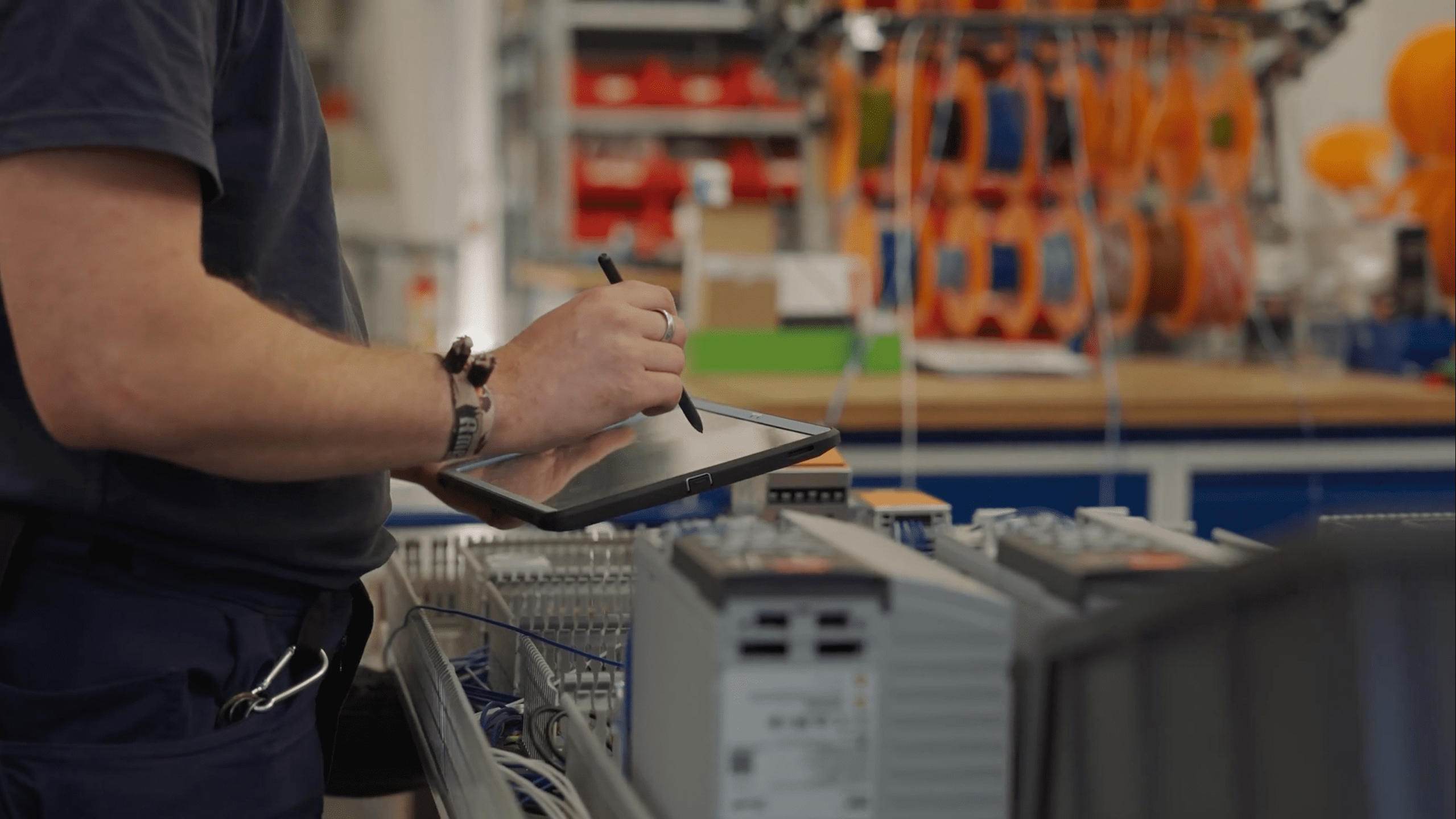 Person mit Tablet arbeitet an technischen Anlagen in Werkstattumgebung.
